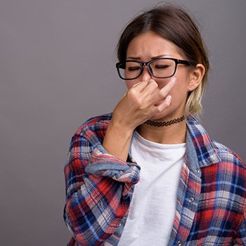 Young beautiful woman holding her nose